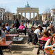 People enjoy sunny weather at the Brandenburg Gate in Berlin